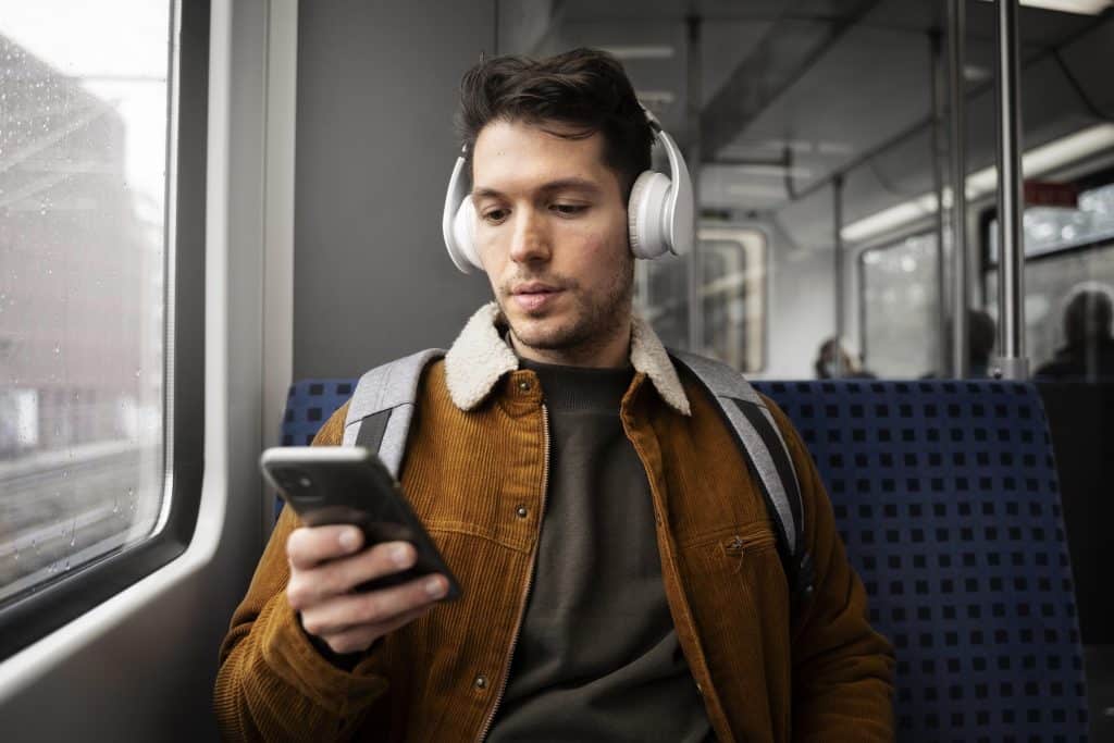 Man hacking his daily commute for more joy by enjoying a peaceful train ride with music on headphones.